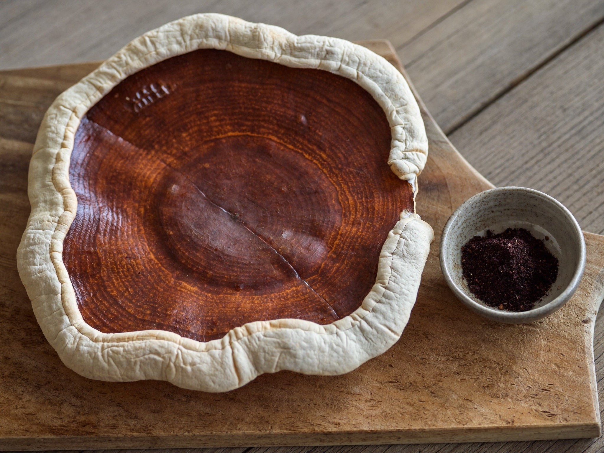 Gedroogde reishi-paddenstoelen en reishi-poeder op een houten plank
